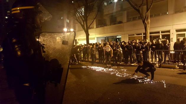 Youths use candles to write the word ‘violence’ in the road in front of a line of riot police outside the commisariat of the 19th district of Paris on Monday night. (AFP) Youths use candles to write the word ‘violence’ in the road in front of a line of riot police outside the commisariat of the 19th district of Paris on Monday night. (AFP)