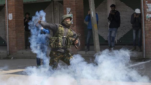 A policeman throws back an exploded tear gas shell at Kashmiri protesters during a protest in Srinagar.(AP Photo)
