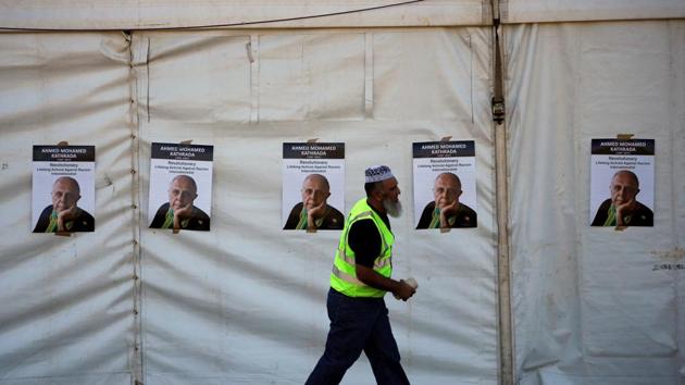 A worker walks past posters bearing the face of Veteran South African anti-apartheid activist Ahmed Kathrada. (Siphiwe Sibeko/REUTERS) 