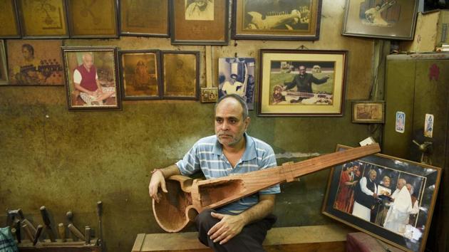 53-year-old Sarod maker Tapan Sen seen with pictures of classical musicians like Ustad Allauddin Khan, Ali Akbar Khan, Ravi Shankar, Amjad Ali Khan in the backdrop, at Hemen & Co. Sons of renowned sarod maker Hemen Sen (the owner of Hemen & Co) - Ratan Sen and Tapan Sen look after the business now. (Samir Jana/HT PHOTO)