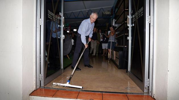 Australian Prime Minister Malcolm Turnbull wipes flood waters out of a building as he visits areas of Bowen in northern Queensland damaged by Cyclone Debbie on March 30.(AFP Photo)