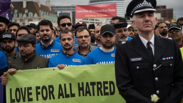 A police officer and British Muslims (blue T-shirt) take part in a vigil on Westminster Bridge. A 30-year-old man remains in custody and a 32-year-old woman has been bailed, having been arrested on suspicion of the same offence. (Oli Scraff/AFP) 