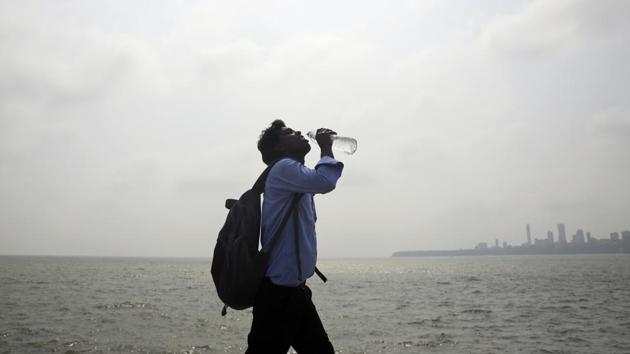 A man takes a drink as he walks by the Arabian sea in Mumbai on Thursday. Maharashtra is experiencing a heat wave condition with temperatures crossing 40 degrees Celsius in several areas.(AP Photo)
