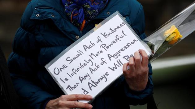 A muslim man holds a flower and a message on a placard as he stands in line with others on Westminster Bridge. (Stefan Wermuth/REUTERS) 