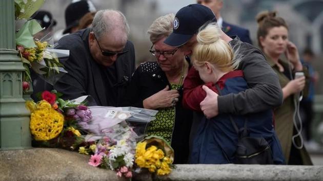 People embrace after laying flowers during an event. Hundreds of people gathered at Westminster Bridge and outside the Houses of Parliament for a silent vigil to commemorate the four people who were murdered in last week’s terror attack. (Hannah McKay/Reuters) 