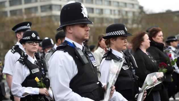 Police officers carry flowers during the event. The police presence was highly visible on the bridge, with police vans and mounted officers securing the ends of the bridge, and others in uniform mingling with the crowd, along with a number of heavily armed officers carrying semi-automatic weapons. (Hannah McKay/REUTERS) 