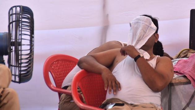 An officer covers his face with a wet cloth in a desperate bid to escape the sweltering sun. (Prashant Waydande/HT )