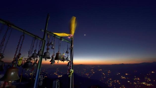 The planet Venus, center, adds a spark to the twilight sky, framed here with the foreground of temple bells outside the Kartik Swami Temple. (Gurinder Osan/HT Photo)