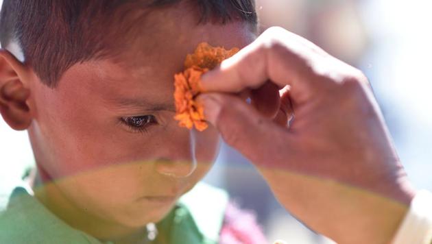 A special 'teeka' or forehead mark, made of turmeric is placed using a marigold flower by the priest at the holy temple. (Gurinder Osan/HT Photo)