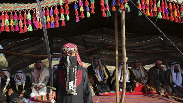 A bedouin girl wears traditional dress holds a sword while posses in front of a tent during a rally. (Adel Hana / AP)