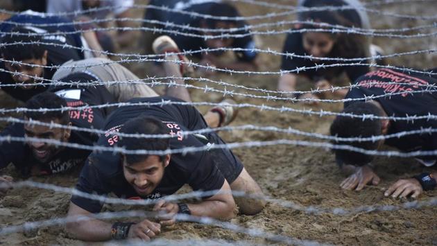 The 5km running course was designed with over 20 military-style obstacles that saw participants clinch their teeth as they ran through muddy tracks, slush pits, tunnels, climb crafted walls to reach the finish line. (Arijit Sen/HT Photo)