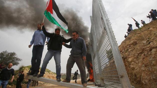 Palestinian demonstrators try to remove a section of the Israeli barrier fence during a protest marking Land Day in the West Bank city of Beit Jala on March 30, 2017. (Mussa Qawasma/REUTERS)