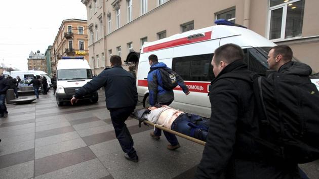 People carry a blast victim to an ambulance after the explosion. Life News website showed pictures of blown-out train doors and injured people on a station platform. (AP/PTI) People carry a blast victim to an ambulance after the explosion. Life News website showed pictures of blown-out train doors and injured people on a station platform. (AP/PTI)