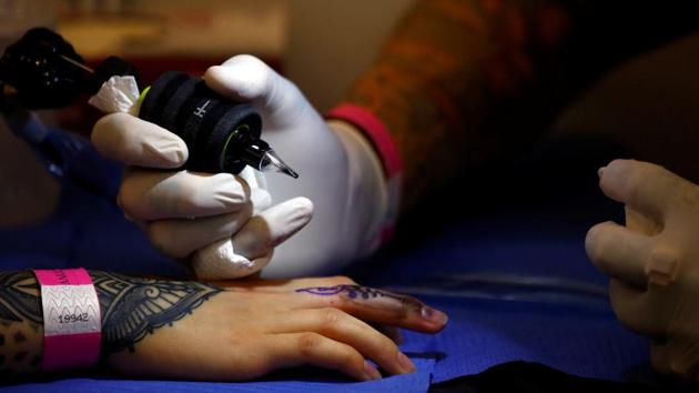 A tattoo artist tattoos on a finger . (Navesh Chitrakar / Reuters)