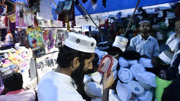 A devotee checks his scull cap before buying it from the market at shrine of Sufi saint Hazrat Khwaja Syed Nizamuddin Auliya. (Burhaan Kinu/HT PHOTO)