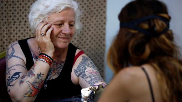 A woman smiles as she gets a tattoo . (Navesh Chitrakar / Reuters)