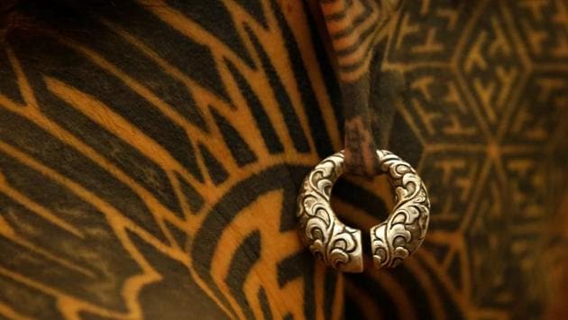 An earring is pictured on a man with tattoos on his face and neck . (Navesh Chitrakar / Reuters)