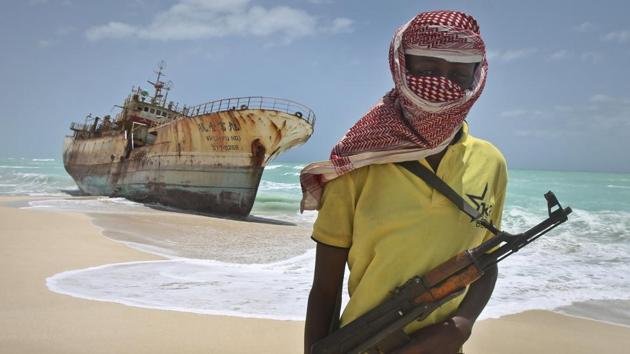 In this file photo, a masked Somali pirate stands near a Taiwanese fishing vessel that washed up on shore after the pirates were paid a ransom and released the crew, in the once-bustling pirate den of Hobyo, Somalia.(AP File Photo)