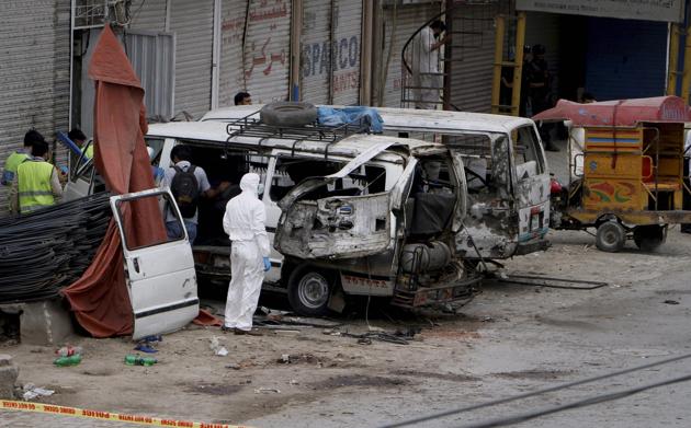Investigators examine damaged vehicles at the site of the blast in Lahore.(AP)