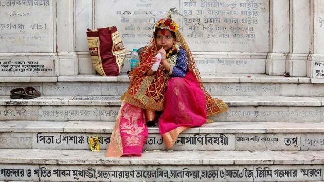 A girl dressed as Kumari, sipping a soft drink as she sits on stairs after attending rituals to celebrate the Navratri Festival inside the Adyapeath Temple, on the outskirts of Kolkata. (REUTERS)