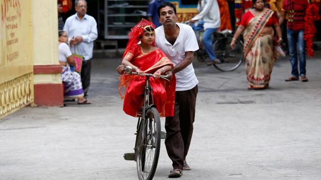 A man carries his daughter, dressed as Kumari, on a bicycle, as they arrive to attend rituals to celebrate the Navratri Festival, inside the Adyapeath Temple, on the outskirts of Kolkata, April 5, 2017. (REUTERS)
