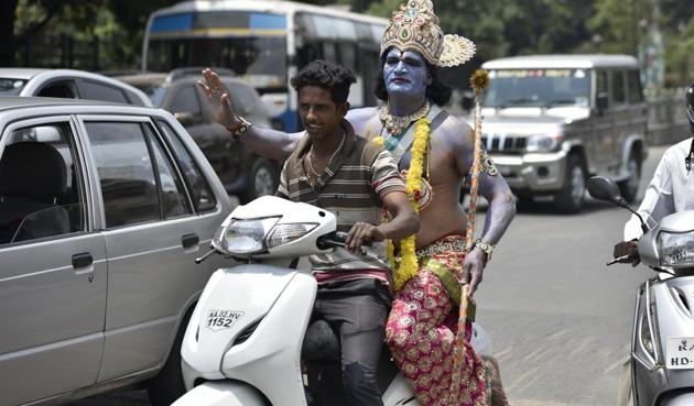 An artist dressed as Lord Ram rides pillion on a scooter before a road show on the occasion 9th day of Navratri at a Hanuman Temple near Kempegowda Railway Station in Bengaluru on Wednesday, April 5, 2017. (Arijit Sen/HT Photo)