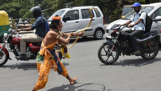 Artists dressed as characters of Ramayana performing amid traffic during a road show on the occasion 9th day of Navratri at a Hanuman Temple near Kempegowda Railway Station in Bengaluru. (Arijit Sen/HT Photo)