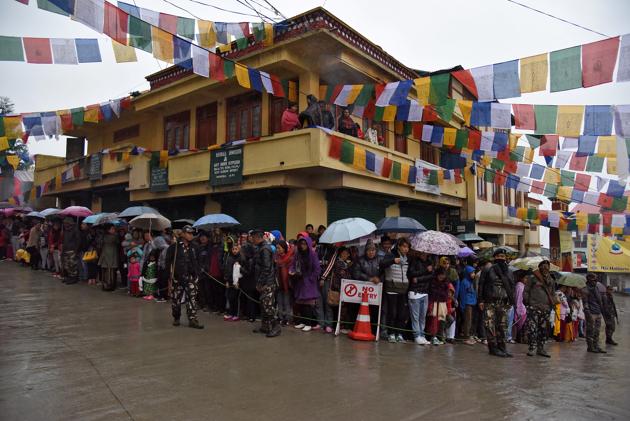 People stand in rain as they wait to welcome Tibetan spiritual leader Dalai Lama in Bomdila. (Anuwar Hazarika / REUTERS)