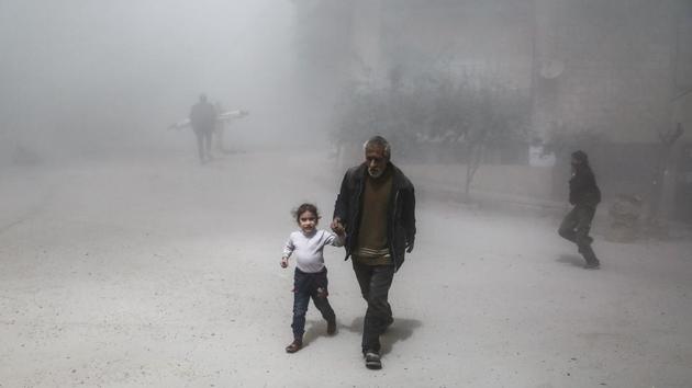 A Syrian man and girl flee following a reported government air strike on the rebel-controlled town of Hamouria, Syria.(AFP Photo)