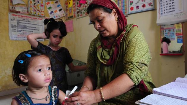 An anganwadi worker conducts a health checkup on a child in Bhopal. Anganwadis have been at the forefront of  vaccination drives including the massive effort made towards vaccination against polio. As no new cases of polio were identified in India in the last two years, it is an effort that has come to fruition. (mujeeb faruqui/ht photo) 
