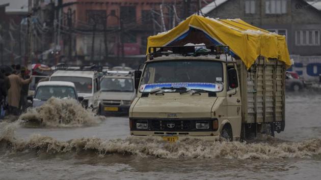 Vehicles navigate their way through a waterlogged street in Srinagar. Shooting stones and landslides at several places along the Jammu-Srinagar national highway has forced the closure of the road as well. (Dar Yasin / AP)