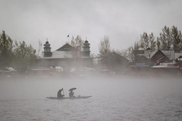 Kashmiri men rides a boat on the Dal Lake amid dense fog after fresh snowfall in Srinagar. (Dar Yasin / AP)