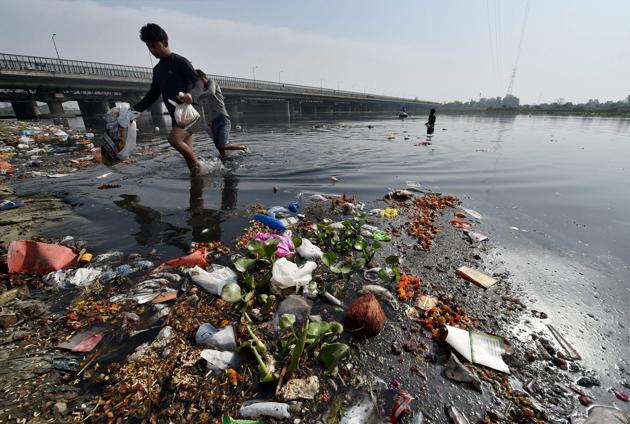 Ragpickers search for coins, gold and offerings in the polluted waters of the Yamuna River after the Navratri festival. (Manvender Vashist/ PTI)