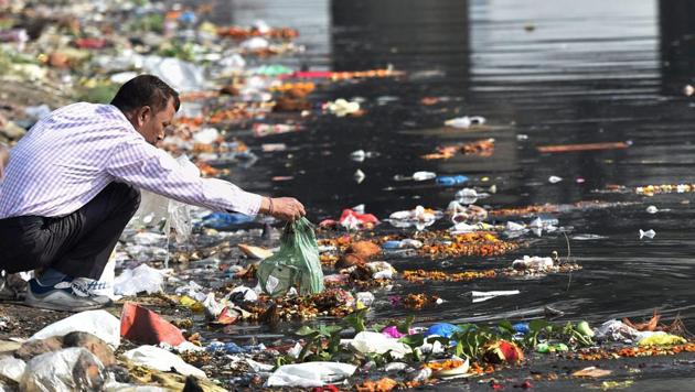 A man throws the puja offerings in Yamuna River at the end of Navratri festival in New Delhi. As the festival of Navratri ended, the rivers are once again in complete mess with several tonnes of flowers, polythene packets and other religious offerings floating on water. (Manvender Vashist / PTI)