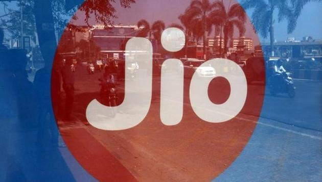 Commuters are reflected on an advertisement of Reliance Industries’ Jio telecoms unit, at a bus stop in Mumbai.(REUTERS)