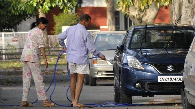 A resident washing his car using a pipe in Sector 7, Chandigarh, on Saturday. The ban on watering of lawns and washing vehicles using running water in the three cities is unlikely to be of much help as the gap bewteen the demand and supply of water is huge.(Karun Sharma/HT Photo)