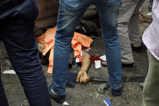 Egyptians gather around a body in a street near a church in Alexandria after a bomb blast struck worshippers gathering to celebrate Palm Sunday on April 9, 2017. (AFP)