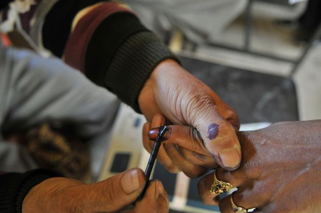 An election official marks the finger of a voter inside a polling station in Baba Nagri area in Kangan, some 50 km from Srinagar.