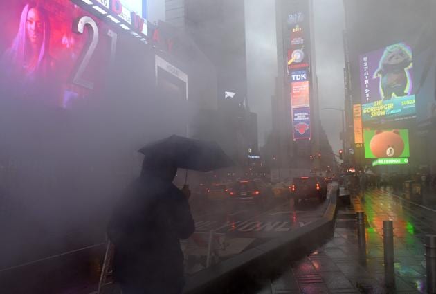 A person walks through Times Square in the early morning rain, as heavy storms are expected to hit the area on April 6, 2017 in New York. (TIMOTHY A. CLARY / AFP)