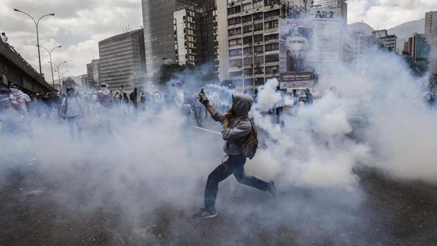 Venezuelan opposition activists react to tear gas shot by the police during protests against the government of President Nicolas Maduro on April 6, 2017 in Caracas. The center-right opposition vowed fresh street protests - after earlier unrest left dozens of people injured - to increase pressure on Maduro, whom they blame for the country's economic crisis. (JUAN BARRETO / AFP)
