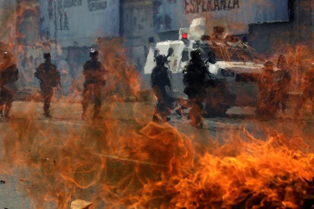 Venezuelan national guards walk behind a burning blockade during clashes with demonstrators during an opposition rally in Caracas, Venezuela, April 6, 2017. (Marco Bello / REUTERS)