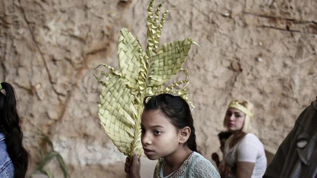 A Christian girl holds palm fonds during a Palm Sunday mass inside the Cave Cathedral or St. Sama'ans Church on the Mokattam hills. (Nariman El-Mofty/AP)
