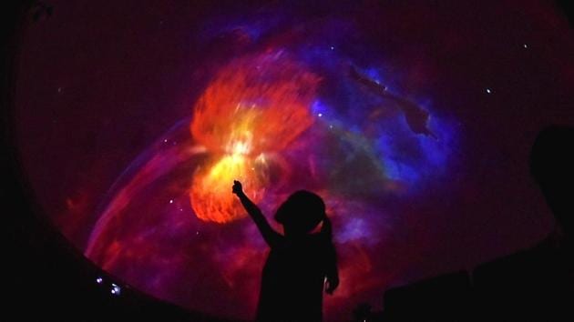 A student pointing out to a vivid display of colours during a screening at the Nehru planetarium sky theatre show in New Delhi. (Raj K Raj/HT PHOTO)