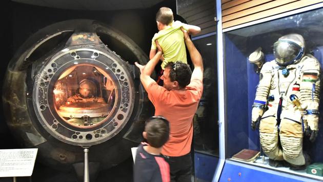 A man holds up a child looking into the Soyuz capsule spacecraft on display. The Soyuz space flight programme was initiated by the Soviet Union in the early 1960s to put a Soviet cosmonaut as part of a Moon landing project. (Raj K Raj/HT PHOTO)