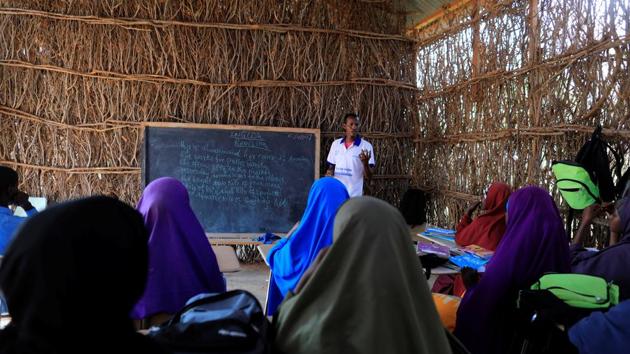 Zeinab's English teacher Abdiweli Mohammed Hersi teaches children at the school near a camp. Between them lie Somalia’s parched sands and the swamps of oil-rich South Sudan, where starving families fleeing three years of civil war survive on water-lily roots. (Zohra Bensemra/REUTERS)