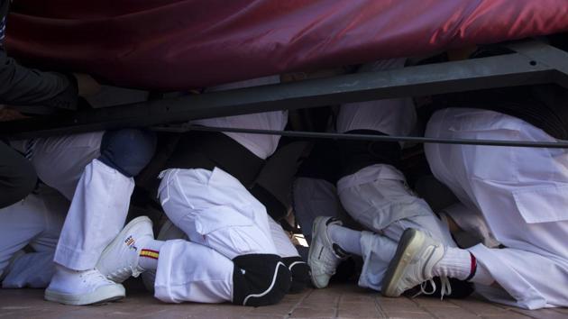 'Costaleros' from the Jesus Despojado brotherhood carry the heavy platform with a religious statue out of the church on their knees during a Holy Week procession in Alcala de Henares in central Spain. (Paul White/AP)