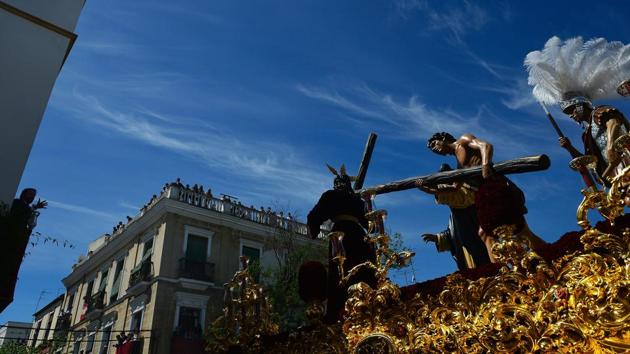 A man (L) sings as the Christ of 'La Paz' brotherhood parade past during the Holy Week. (Cristina Quicler/AFP)