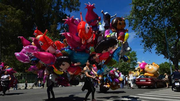 A street vendor holds balloons during the Holy Week parade. (Cristina Quicler/AFP)