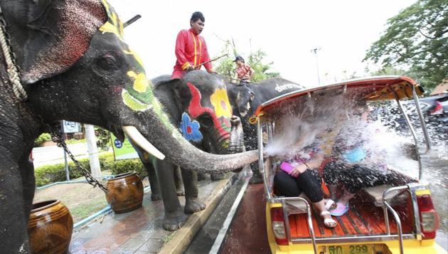 With assist from its mahouts, elephants blow water from its trunk on motor-tricycle or Tuk Tuk at Songkran or ancient Thai New Year celebration . (AP)