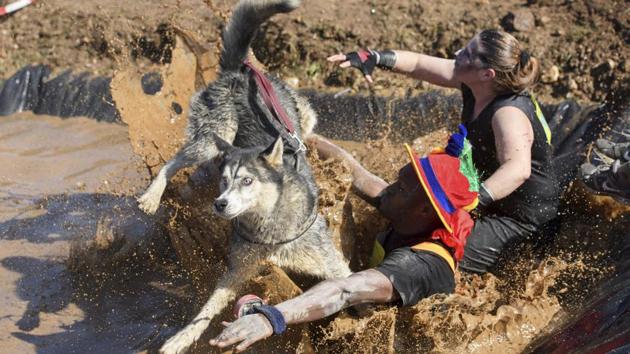 Participants, one with a dog, take part in the 3rd extreme ‘La Barjot Run’ running into the water in Biere, Switzerland. (PTI/ AP)